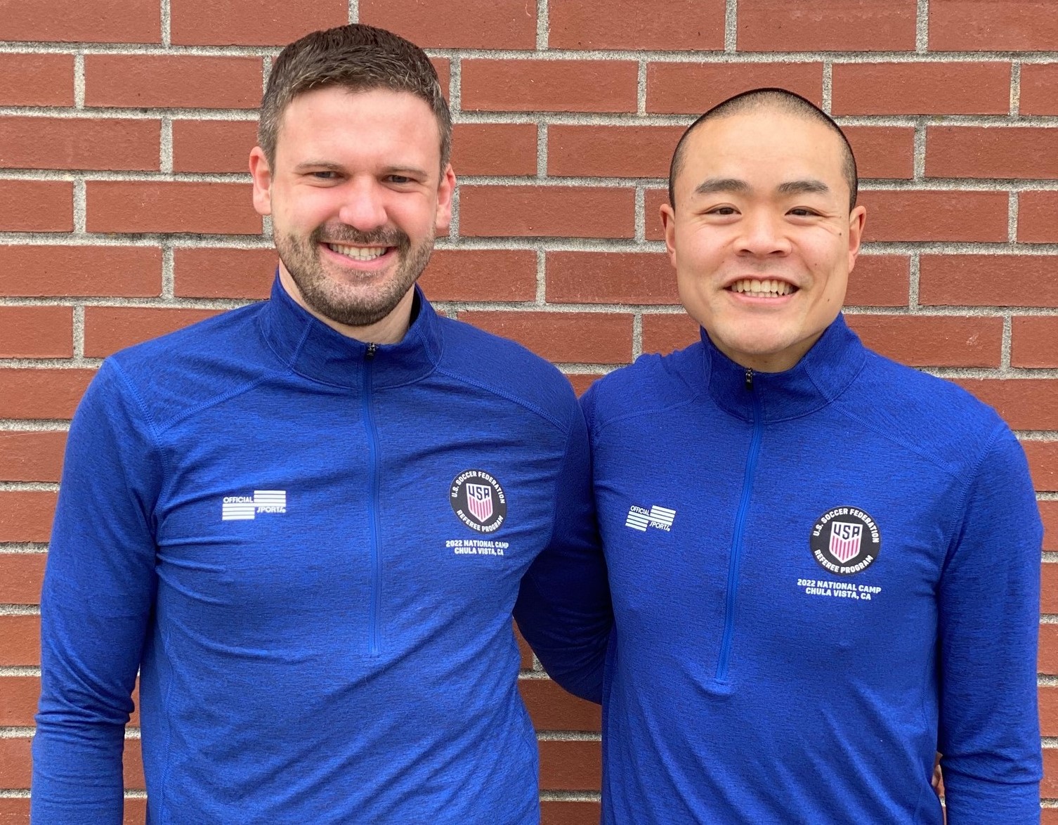 Two male referees in blue smiling together