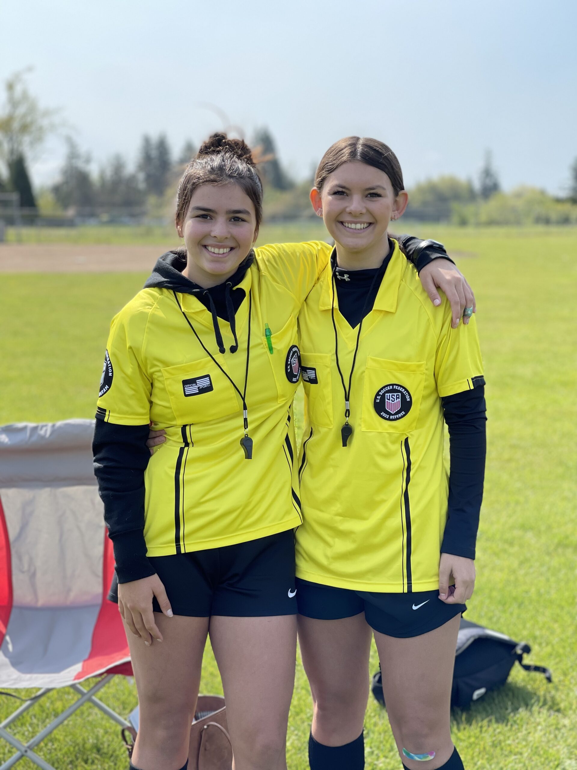 Two female referees in yellow smiling together