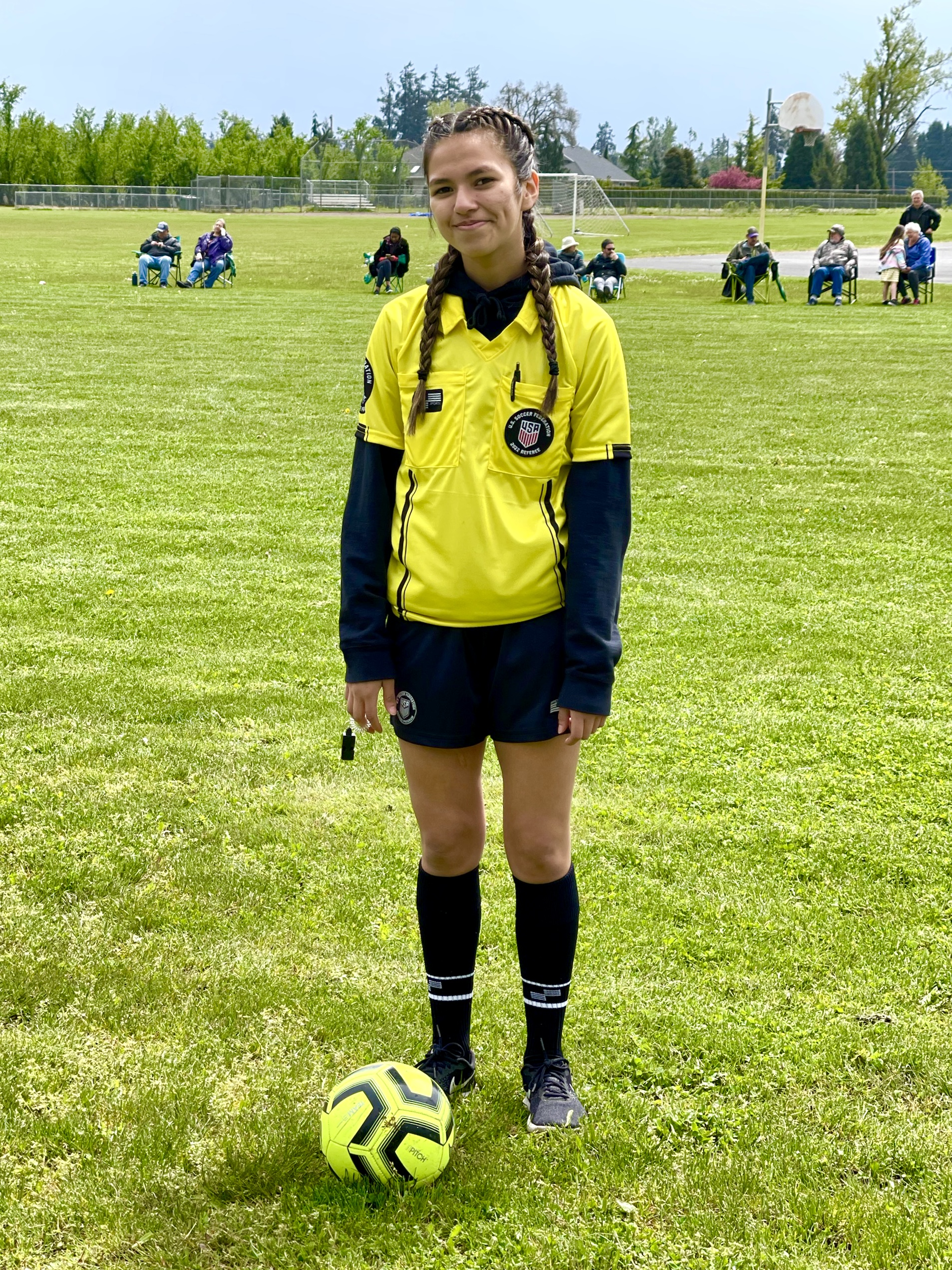 Female referee in yellow with yellow ball smiling