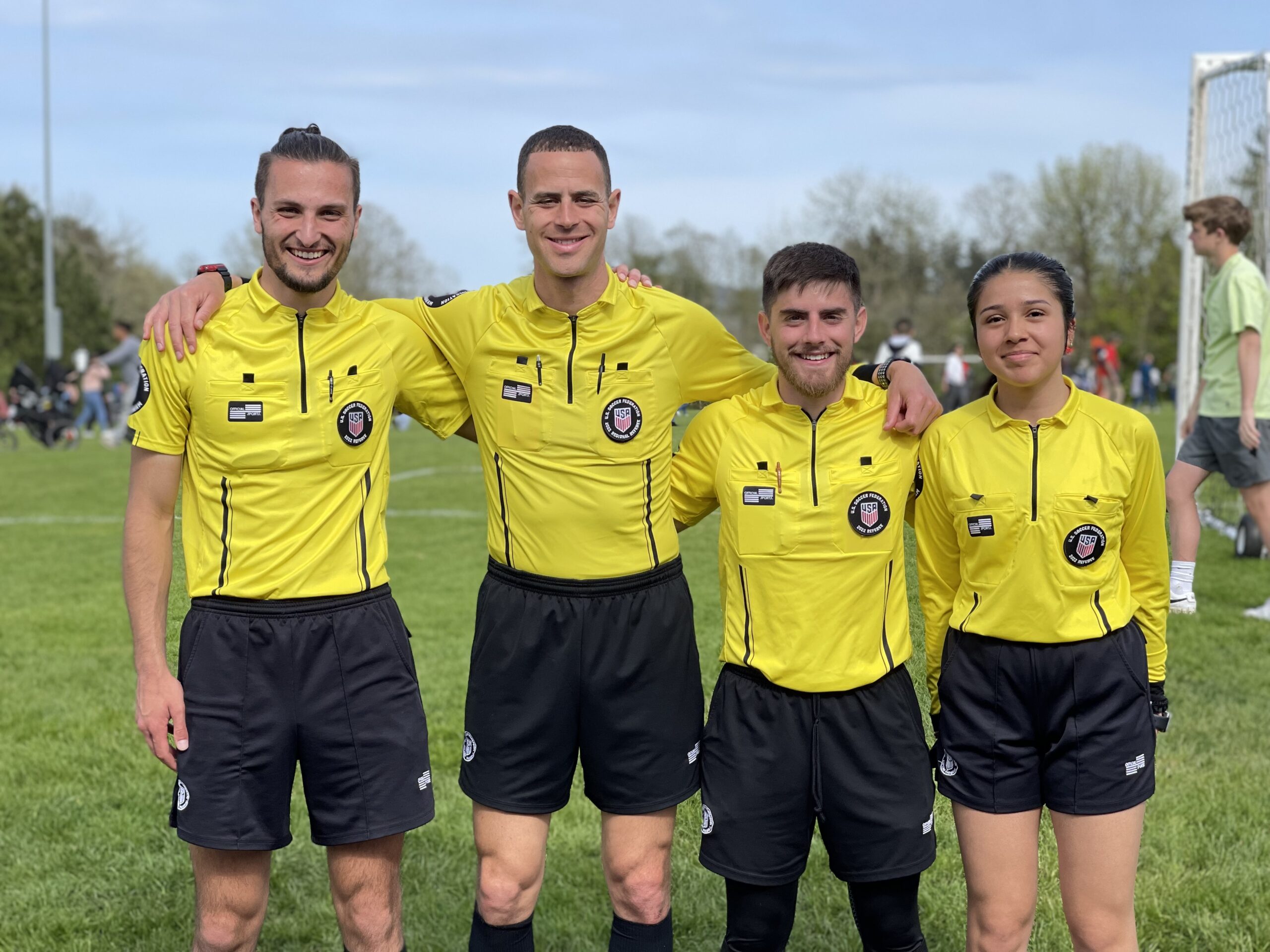 Four referees in yellow smiling